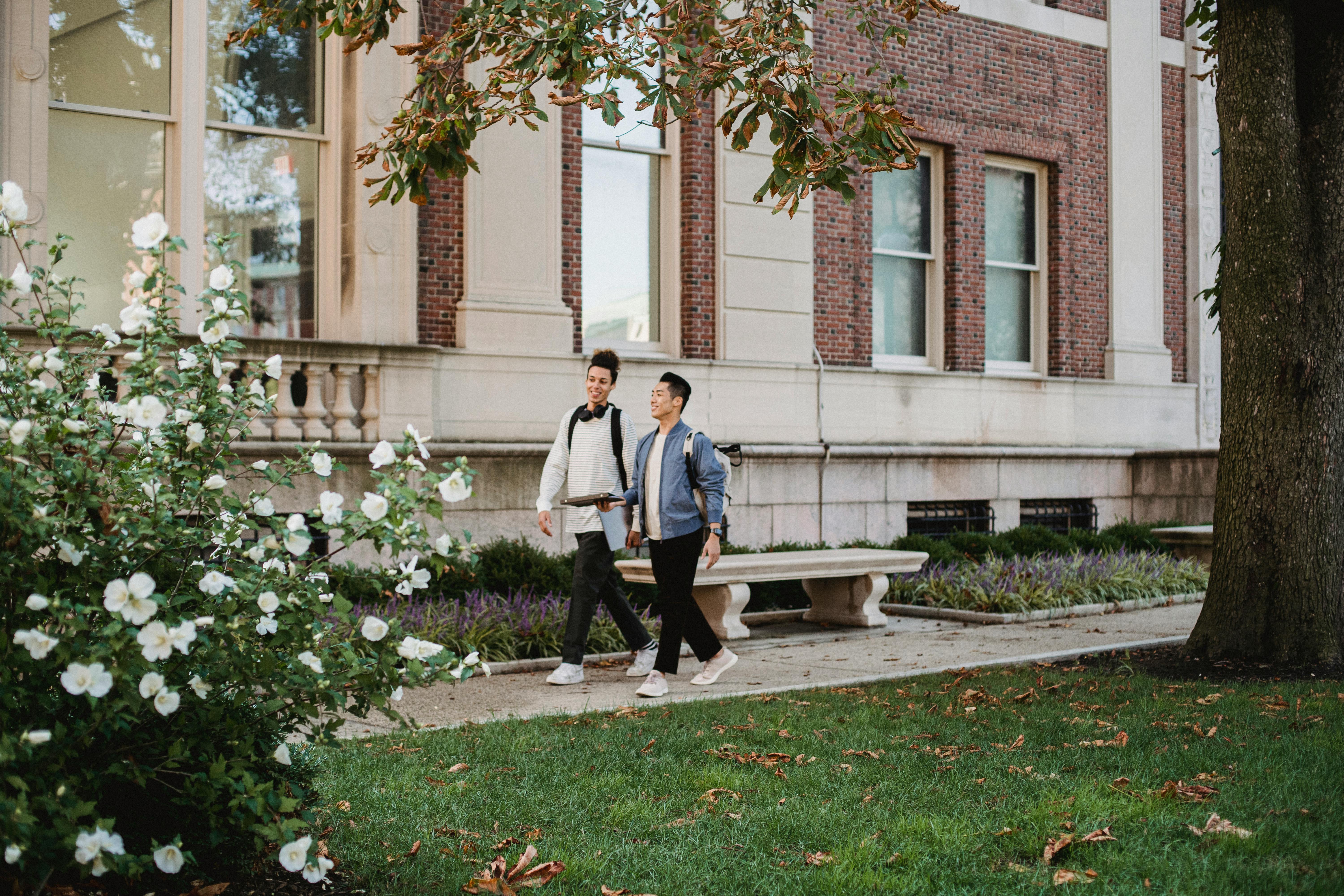 smiling diverse students having talk while walking along campus