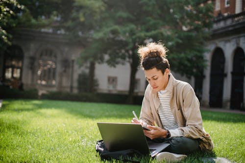 Free Ernsthafter Student, Der Notizen Im Notizblock Schreibt, Während Er Mit Laptop Lernt Stock Photo