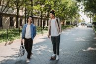一群充满活力的年轻男性朋友，来自不同种族，穿着休闲服装，一边骑滑板一边聊天，在现代城市阳光明媚的人行道上漫步