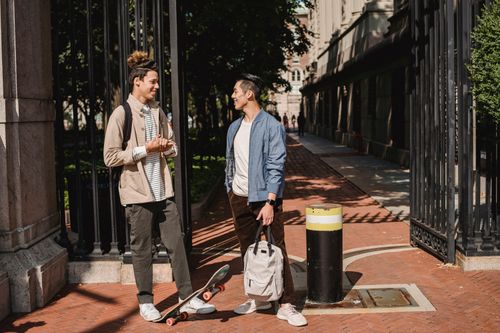 Free Full body positive young male friends wearing street style clothes having conversation on sunny street in modern city Stock Photo