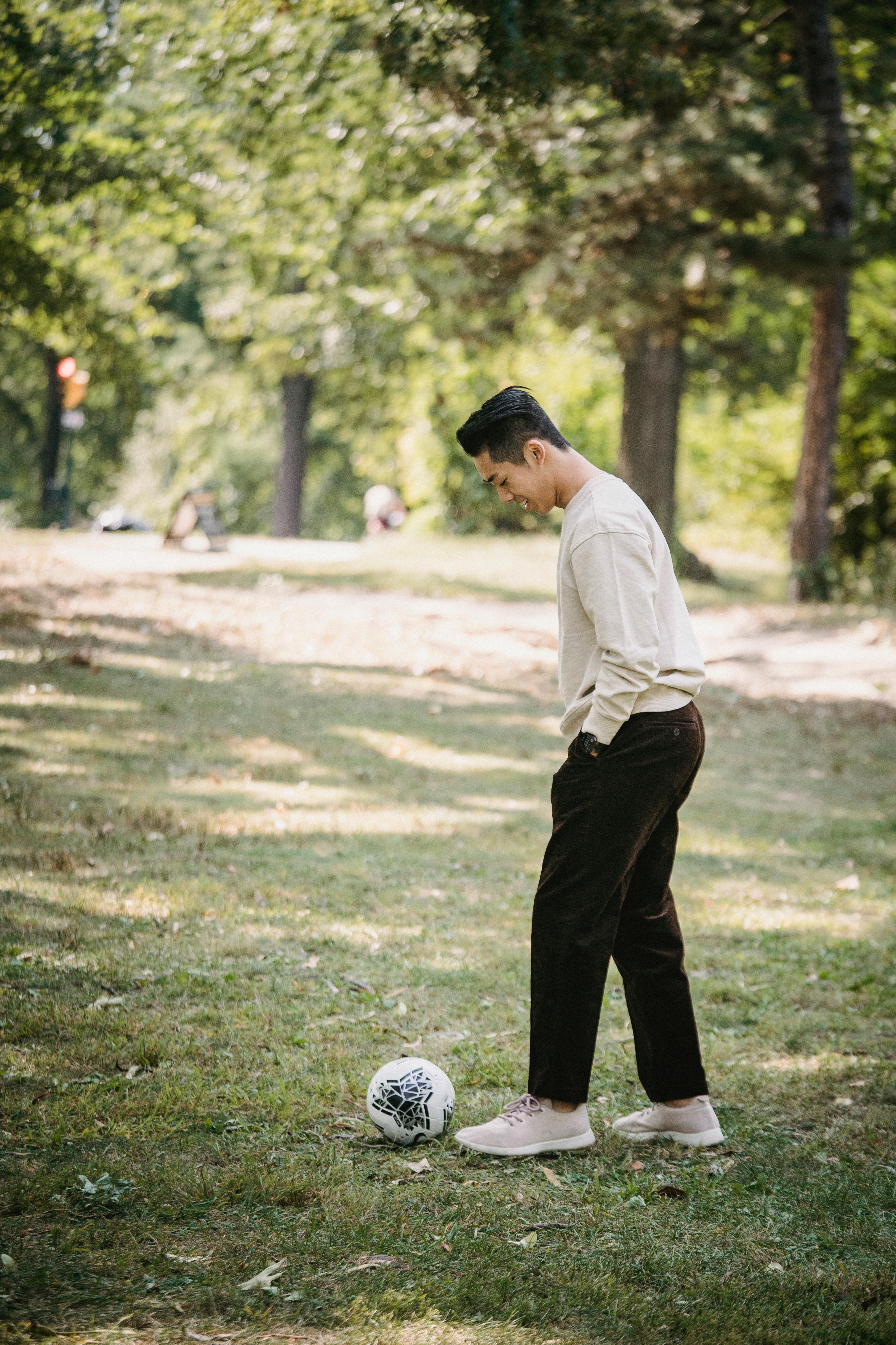 cheerful ethnic man playing with soccer ball in park
