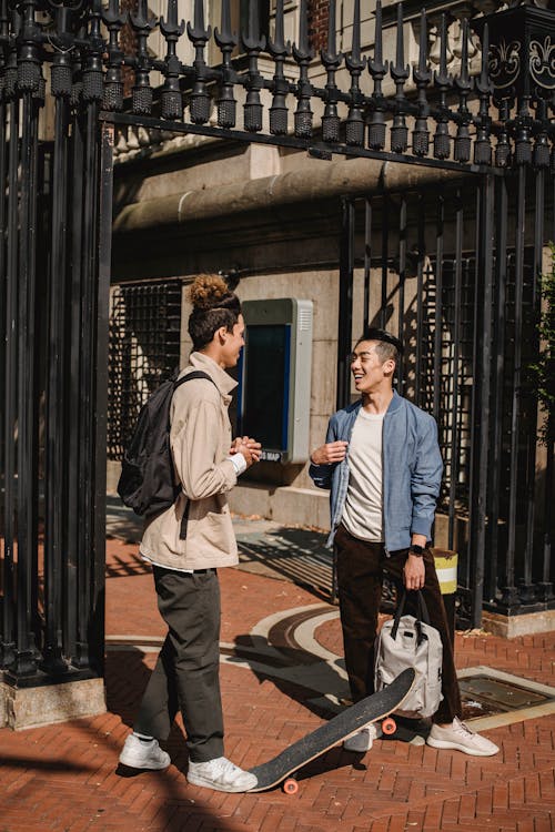 Two Young Men Standing Infront Of A Black Gate