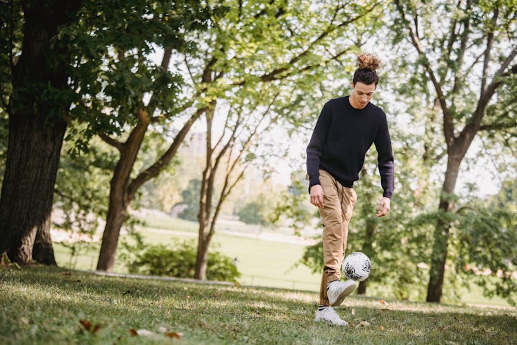 Focused Ethnic Man Tossing Ball In Park