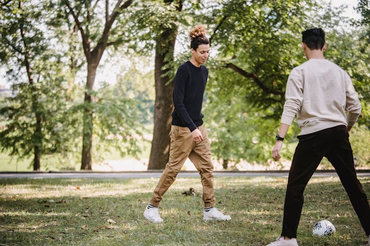 Cheerful Ethnic Male Friends Playing Football In Sunny Park