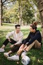 在阳光明媚的公园里，两个年轻人坐在草地上聊天放松