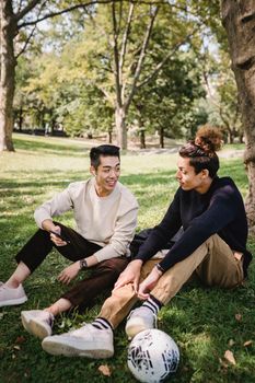 在阳光明媚的公园里，两个年轻人坐在草地上聊天放松