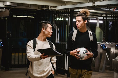 Positive ethnic male friends walking in metro passage