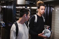 Young men with soccer ball walking in metro station