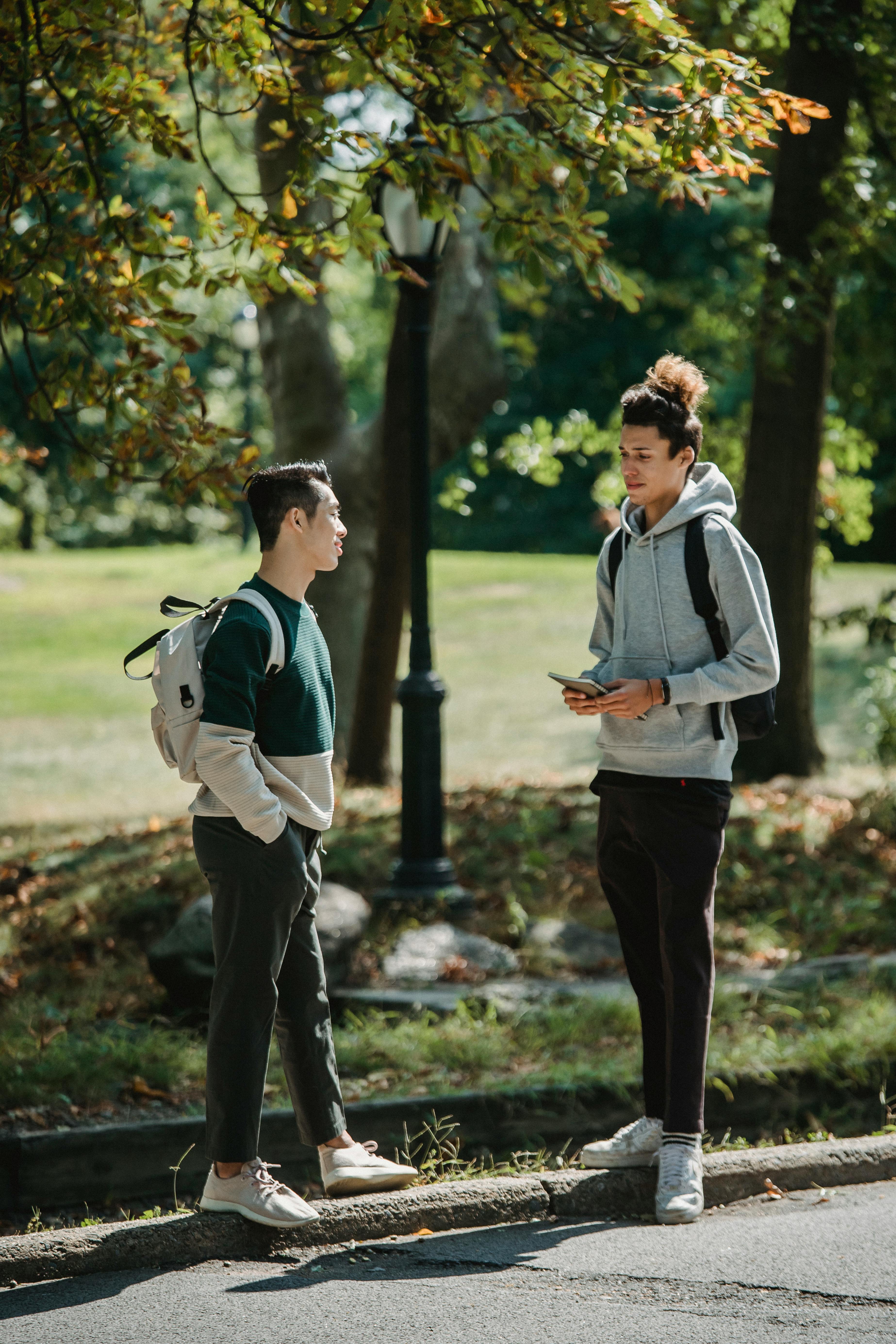 stylish young diverse male millennials chatting in green park on sunny day