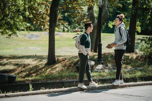 Cheerful young diverse guys chilling in park after school