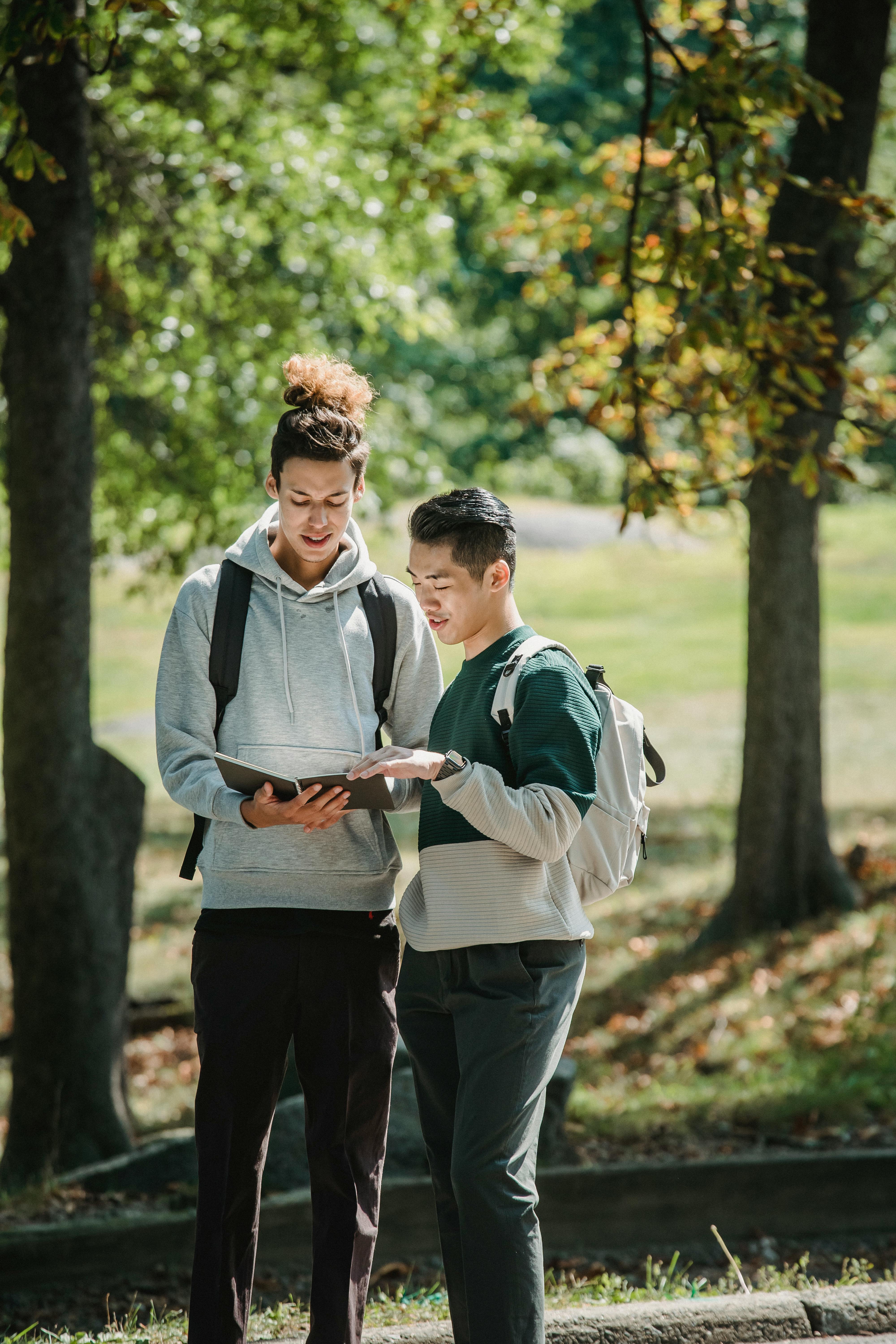 young multiethnic male students reading notepad before college classes