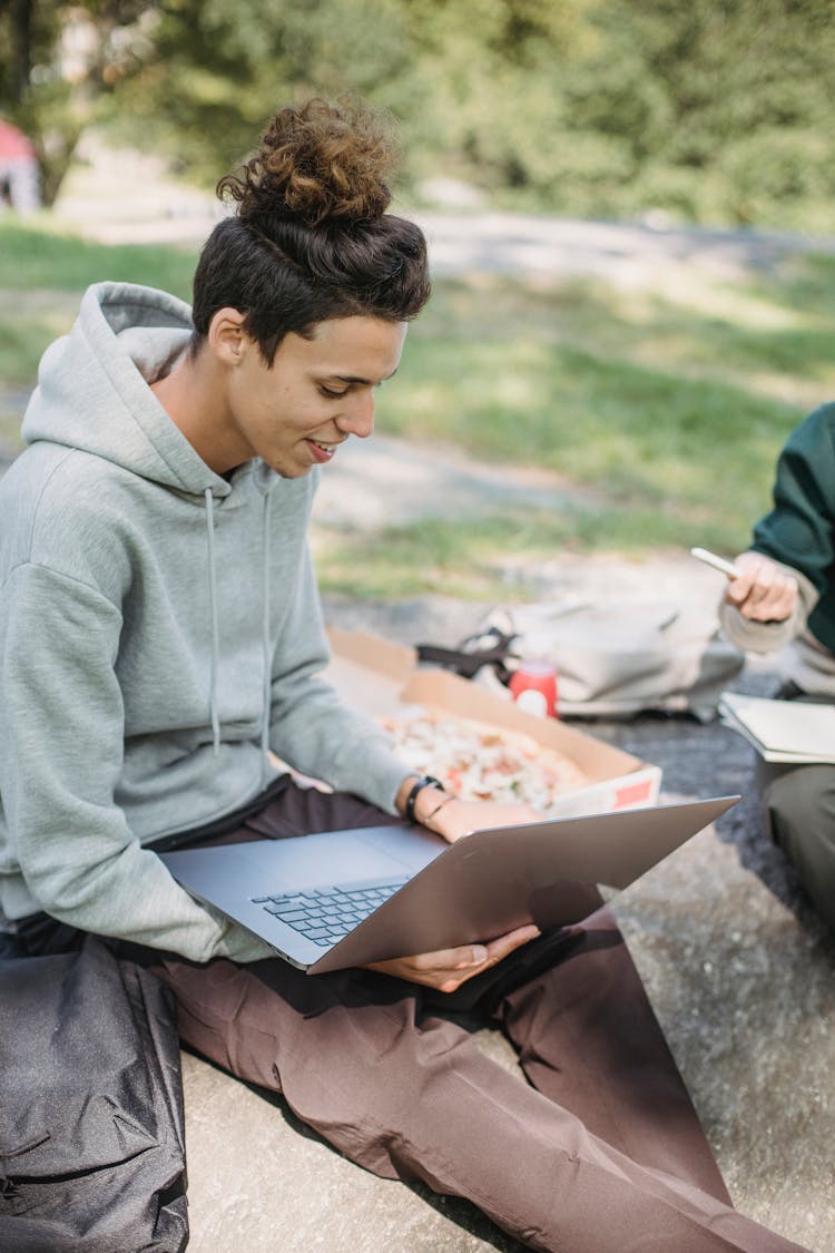 Male Friends Sitting With Netbook And Pizza On Ground