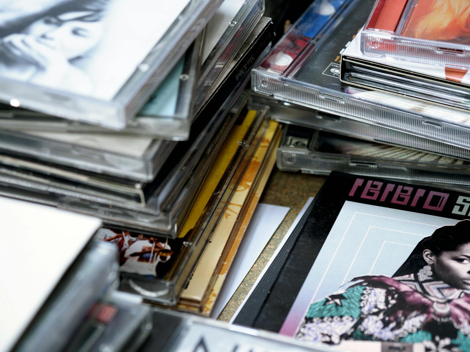 Close-up of stacked music CDs with retro album covers and clear cases in selective focus.