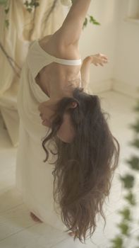 在柔和的室内环境中，一位优雅的女人弯下腰，飘逸的头发散发着平静的气息