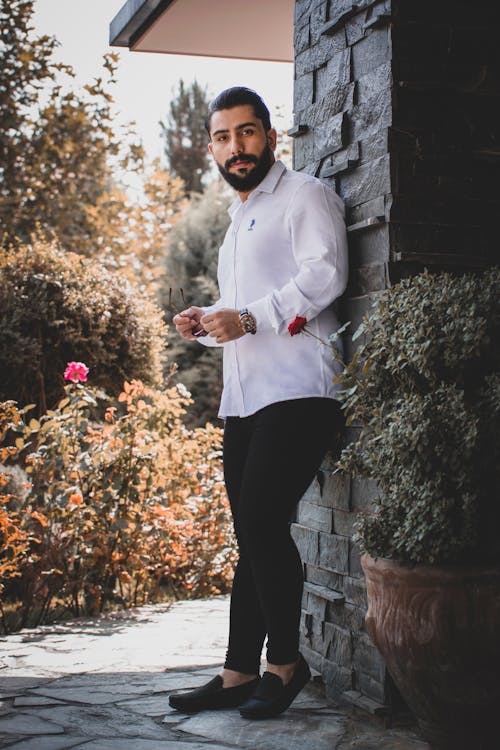 Free Man in White Dress Shirt and Black Pants Leaning on a Stonewall Stock Photo
