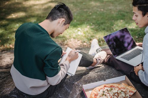 Faceless men resting on boulder with computer