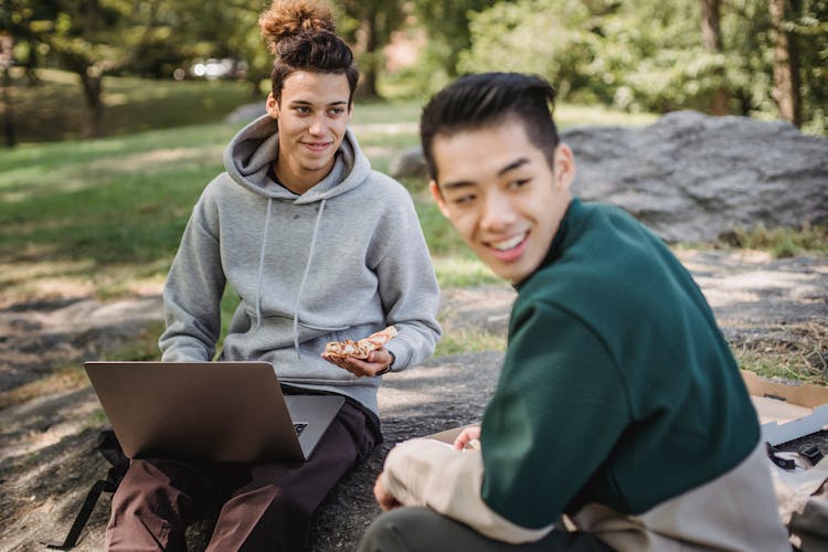 Positive Multiethnic Men Sitting Outside With Laptop