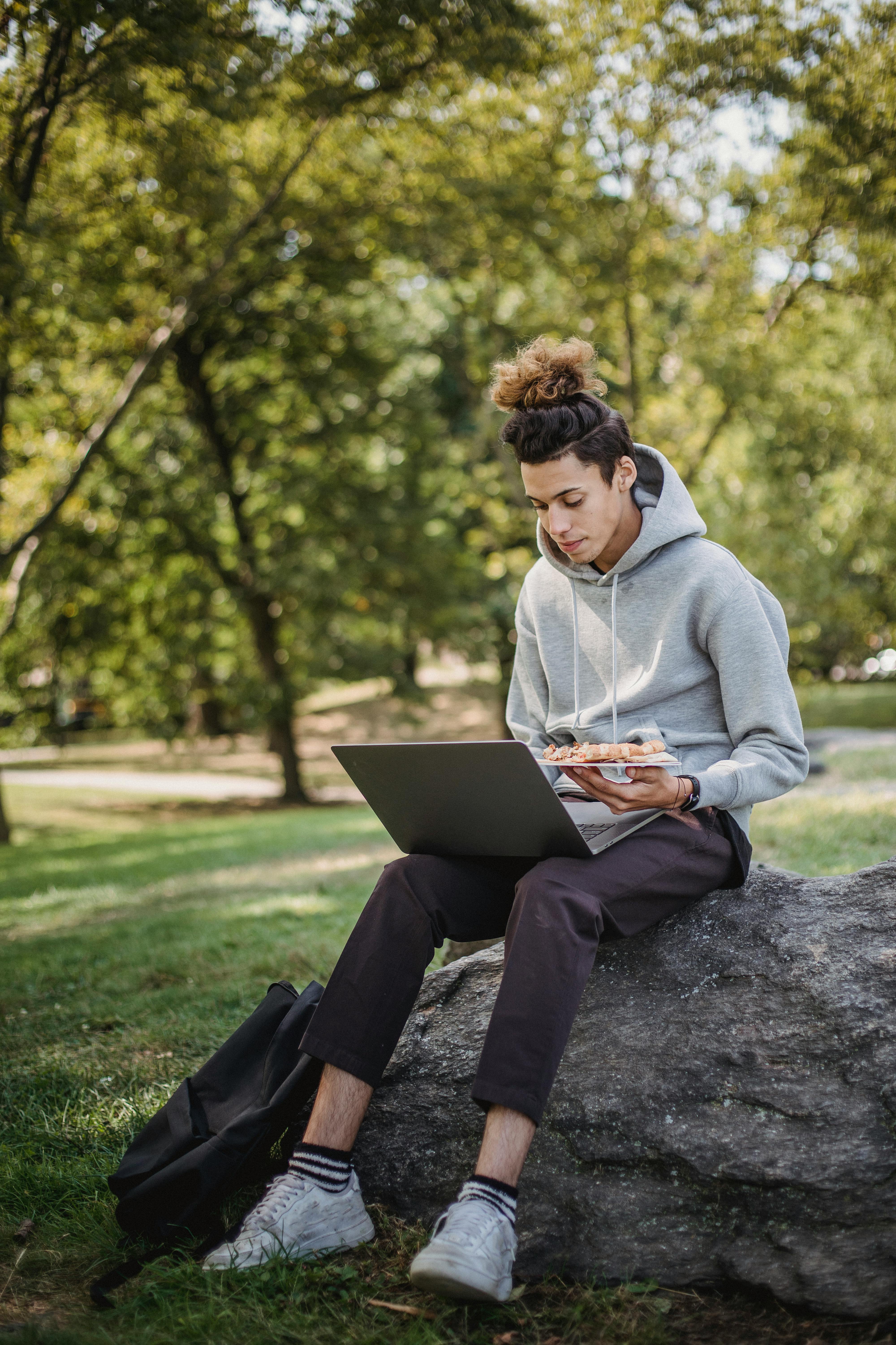 pensive student studying with laptop in park