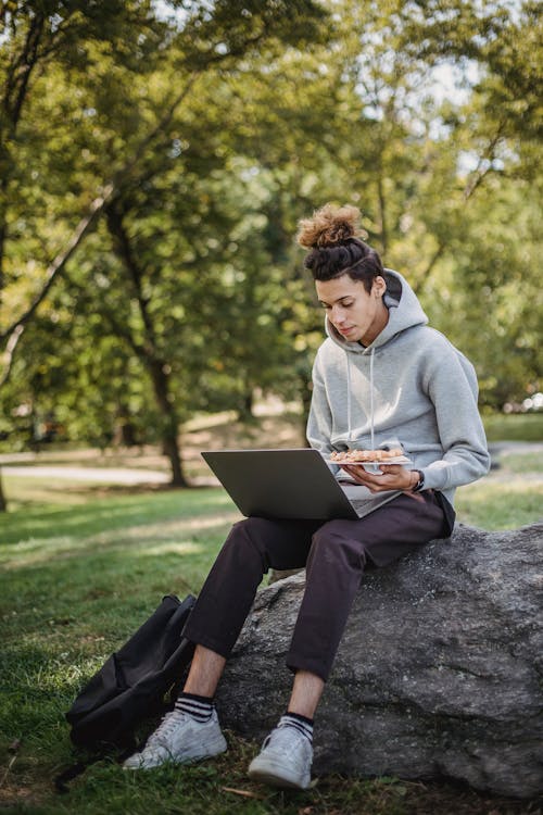 Free Pensive student studying with laptop in park Stock Photo