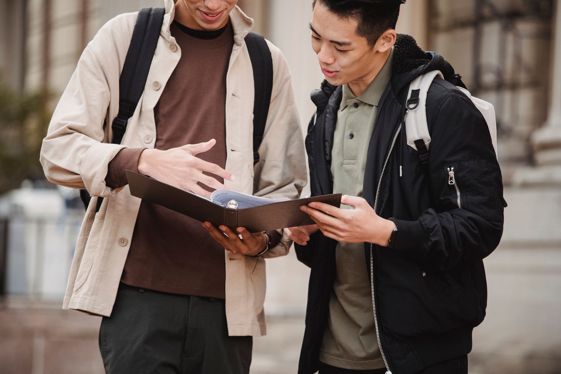 Two young men discussing a project outdoors on a university campus, showcasing collaboration and learning.