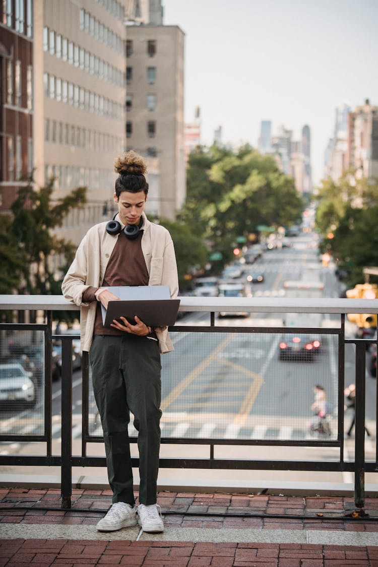 Focused Young Man With Laptop On Footbridge