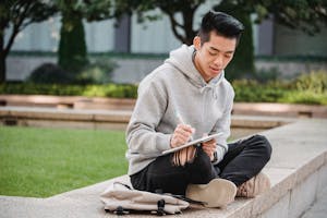 Ethnic man taking notes in notebook