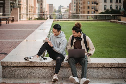 Laughing multiethnic students with laptop and notepad