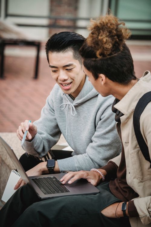 Free Focused young multiracial male students in casual clothes using laptop while working on research and chatting Stock Photo