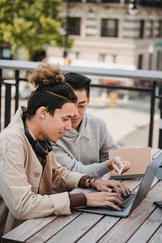 几名穿着休闲服装的年轻多种族男学生围坐在木桌旁，一起做研究的侧视图