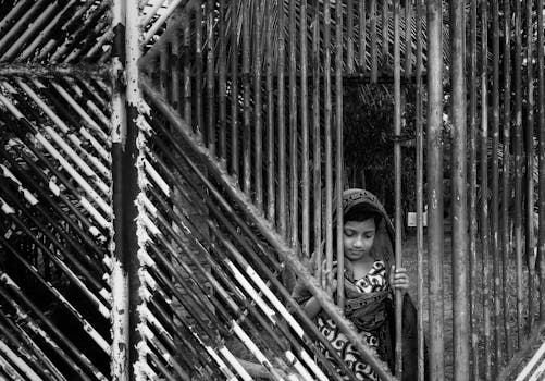 孟加拉国一扇铁大门后，一个孩子的黑白图像传达了隔离的信息