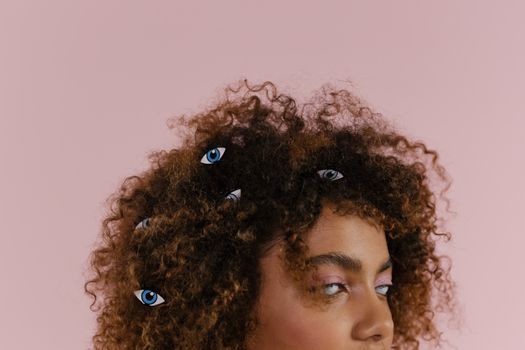 粉红色背景上装饰着超现实的眼球，画面特写一位卷发女人