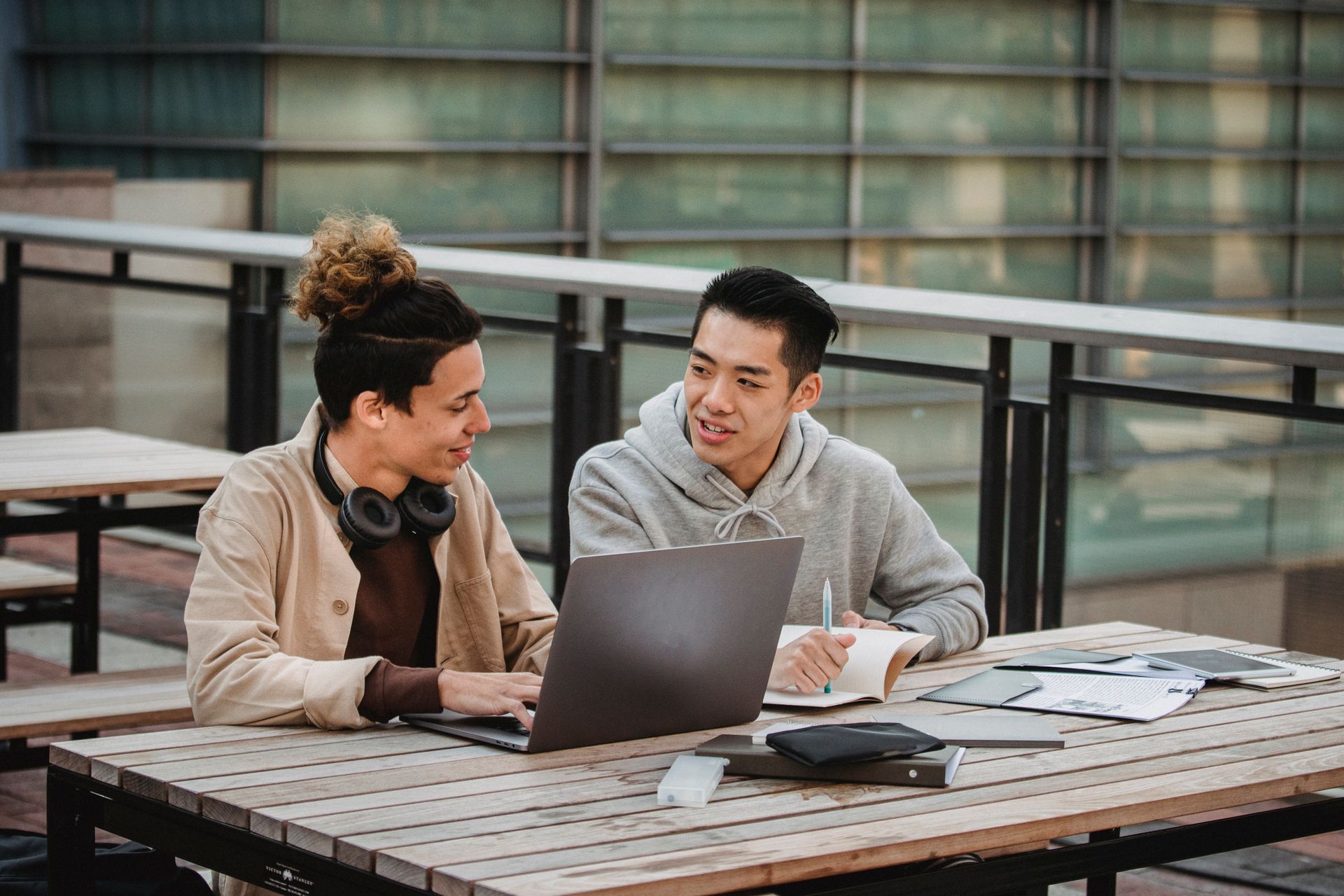 Two young men discussing work together on a campus terrace.