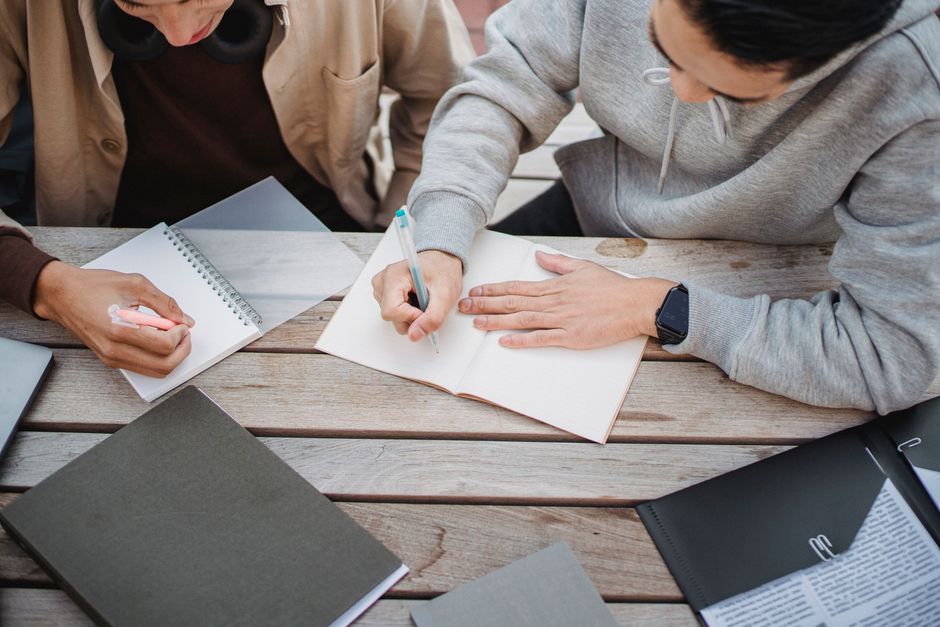 Scholarly Source Use in Research Writing: Fix Common Mistakes 3 From above of crop anonymous male students writing notes in notepads while working on hometask together