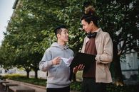 在校园绿荫的环绕下，两名性格各异的年轻人进行了友好的讨论