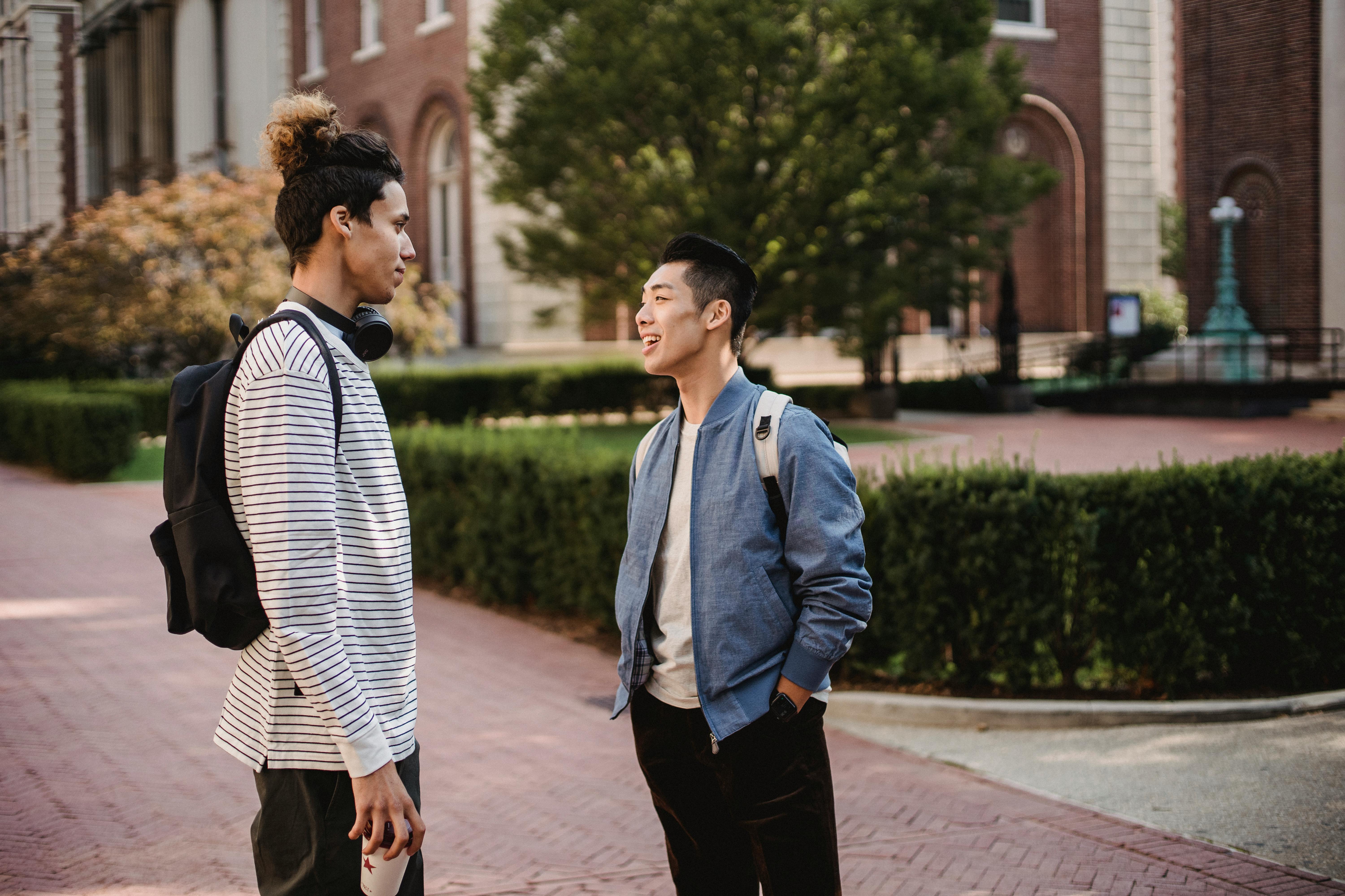 cheerful multiethnic male friends chatting on street