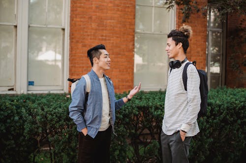 Cheerful multiethnic male friends chatting outside modern building