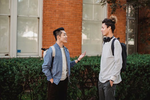 Young men enjoying a friendly chat by a brick building under sunlight.