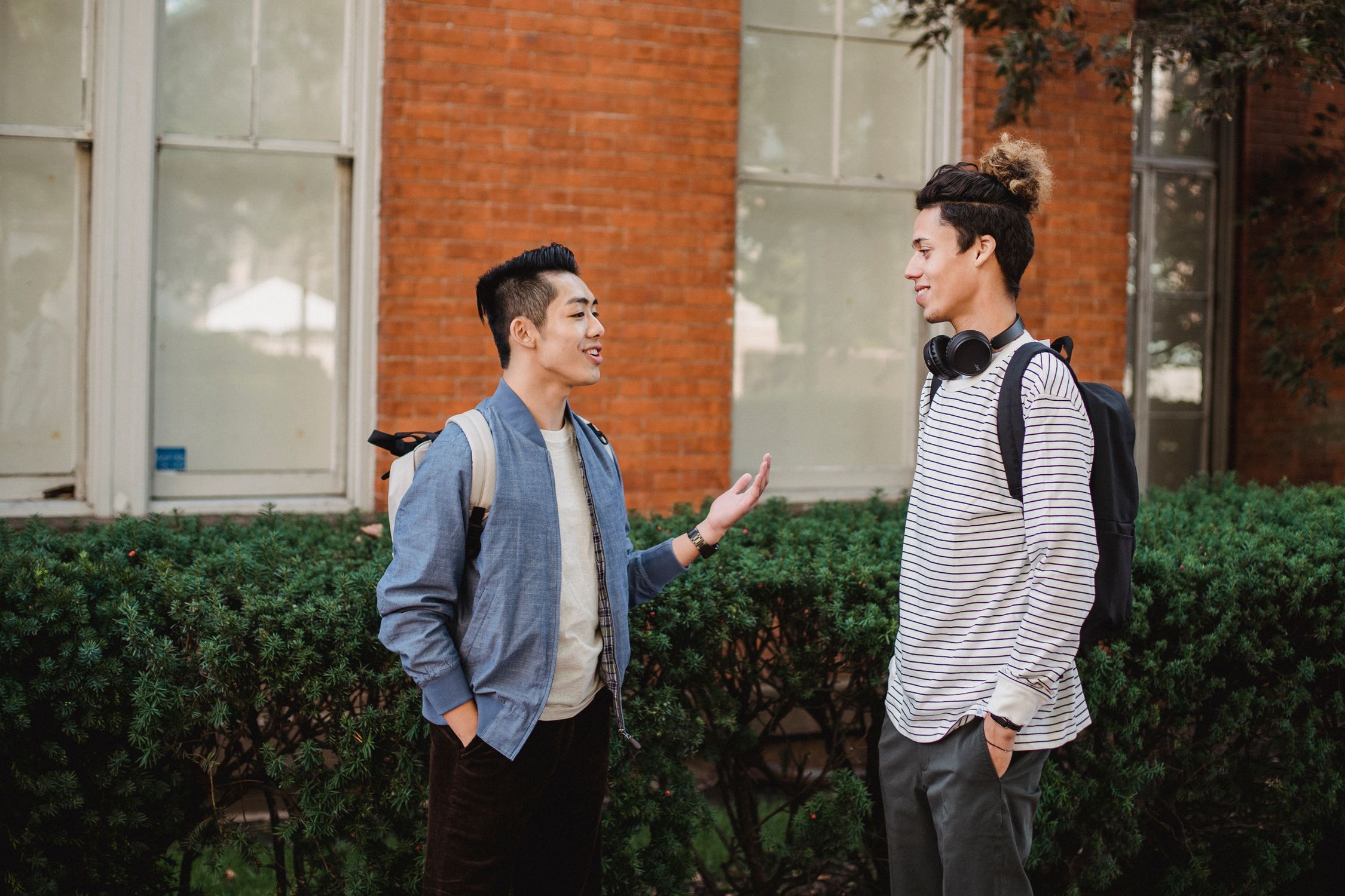 Cheerful multiethnic male friends chatting outside modern building ...