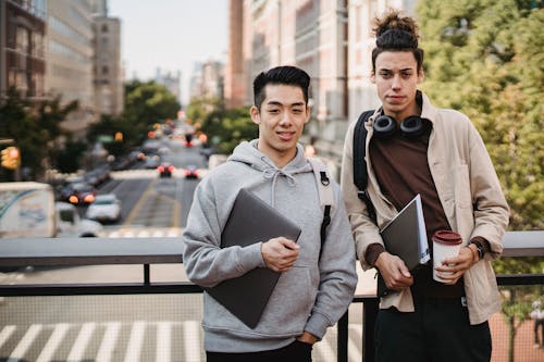 Young diverse men with laptop standing on urban street