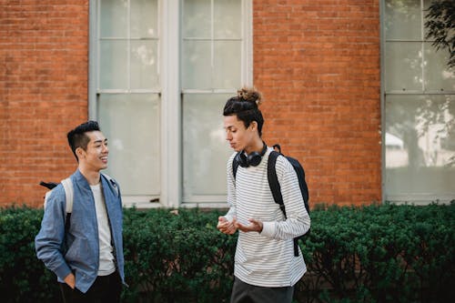 Happy multiethnic male friends chatting outside modern building