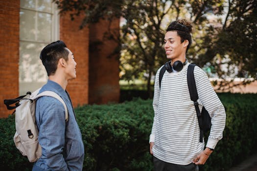 Two college students chatting outside on campus, enjoying a sunny day.