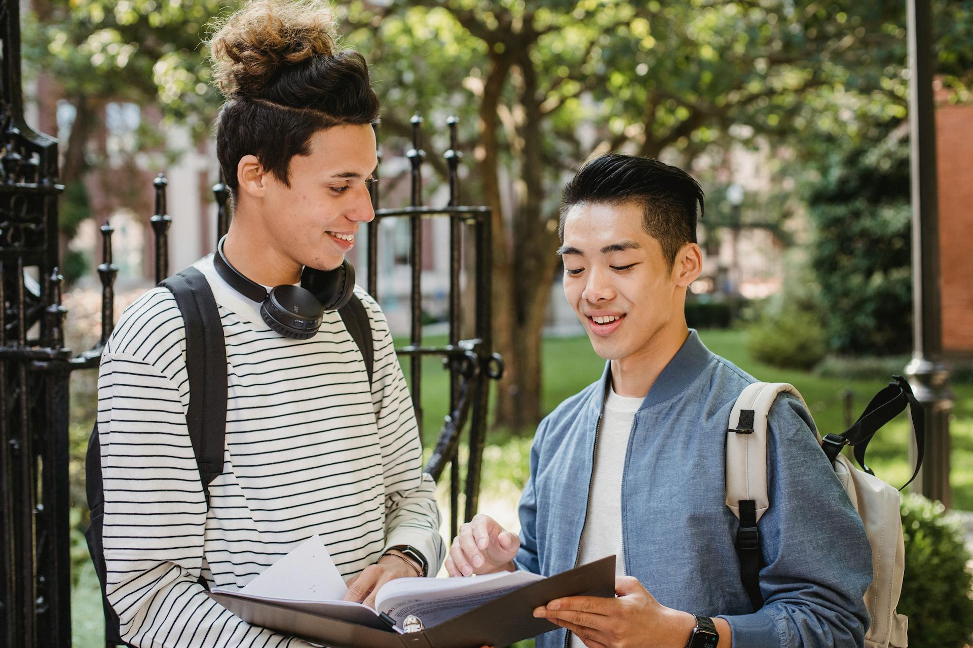 Two young college students engage in a cheerful discussion about their homework on campus.