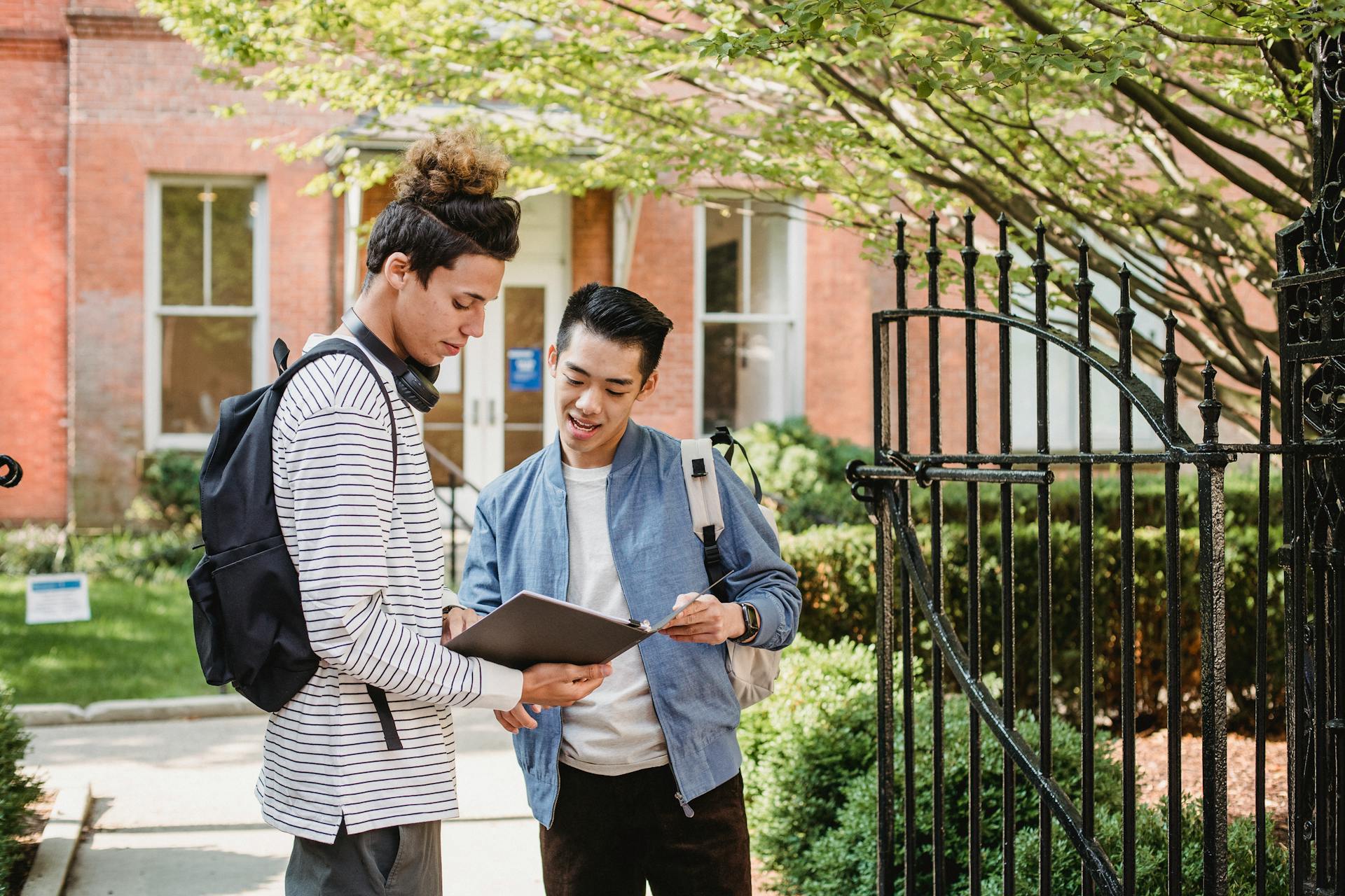 Two university students discussing a project outside on campus. Engaged learning and collaboration in natural setting.