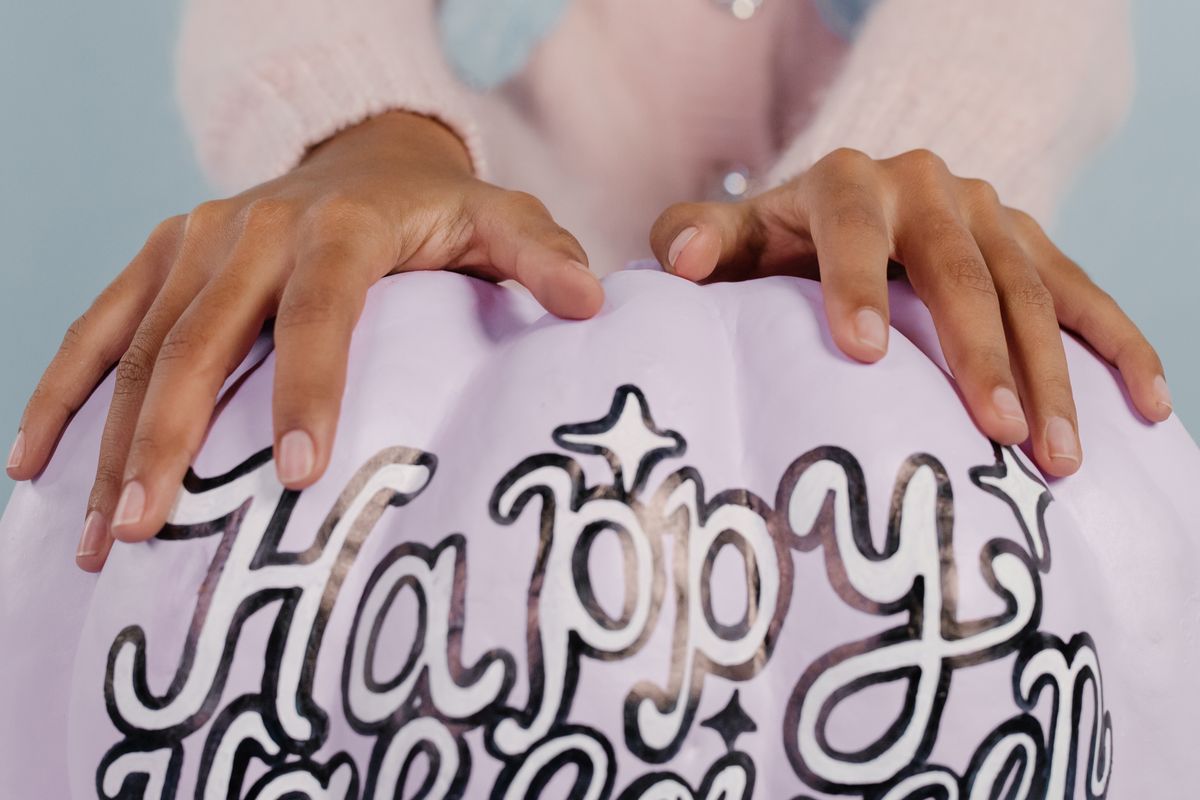 A close-up shot showing hands holding a pastel Halloween pumpkin with text. Stock Photo.
