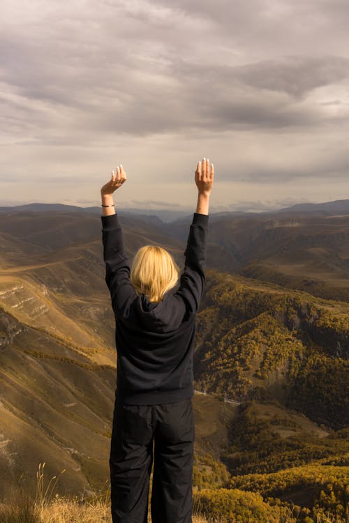 Woman standing with raised hands on hilltop