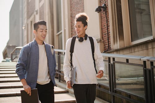 Cheerful multiethnic students walking downstairs with gadget