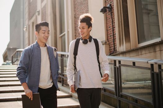 两名年轻男学生在阳光明媚的校园里边散步边聊天