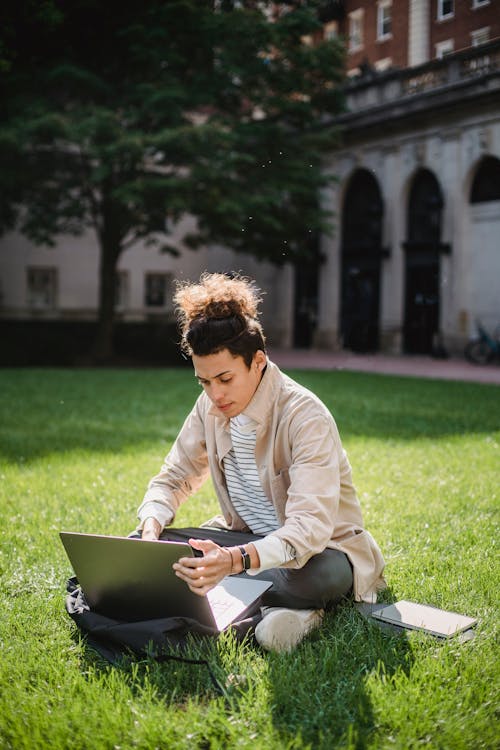 Free Mann In Beige Jacke, Die Auf Grünem Grasfeld Sitzt Stock Photo