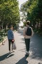 两个年轻人在阳光明媚的公园里散步、玩滑板