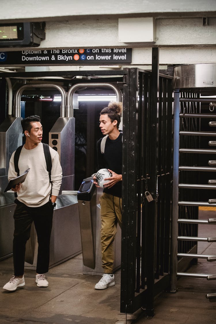 Diverse Male Students Walking Through Turnstiles In Underground